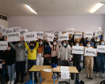 Klasse 6c trägt Schilder mit "Frieden" in verschiedenen Sprachen.
