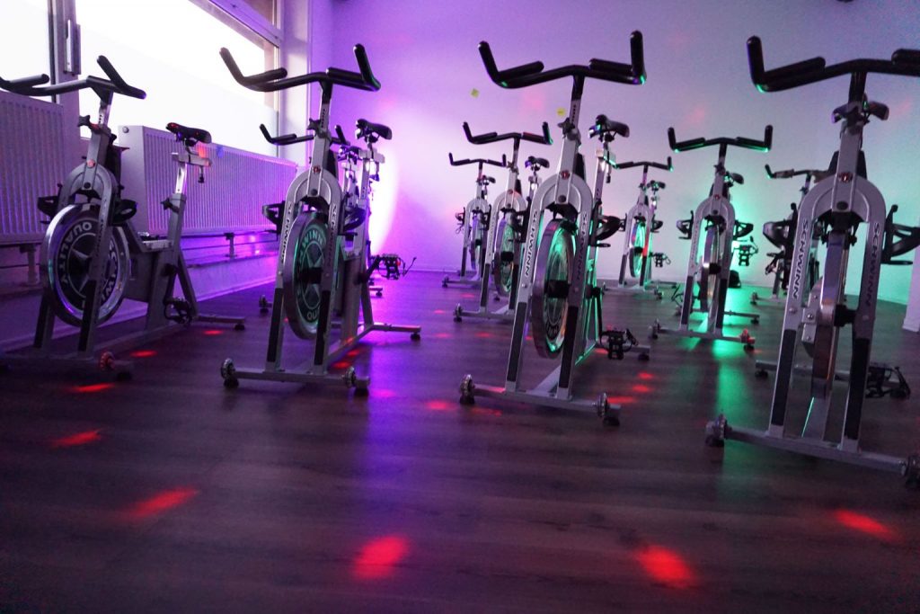Das Bild zeigt den Trainingsraum von Impuls Fitness mit Spinning Rädern.